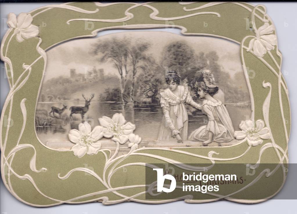 A die-cut Edwardian Christmas Card of two ladies near a lake with deer and a castle all in an art nouveau frame, circa 1910 (coloured lithograph)