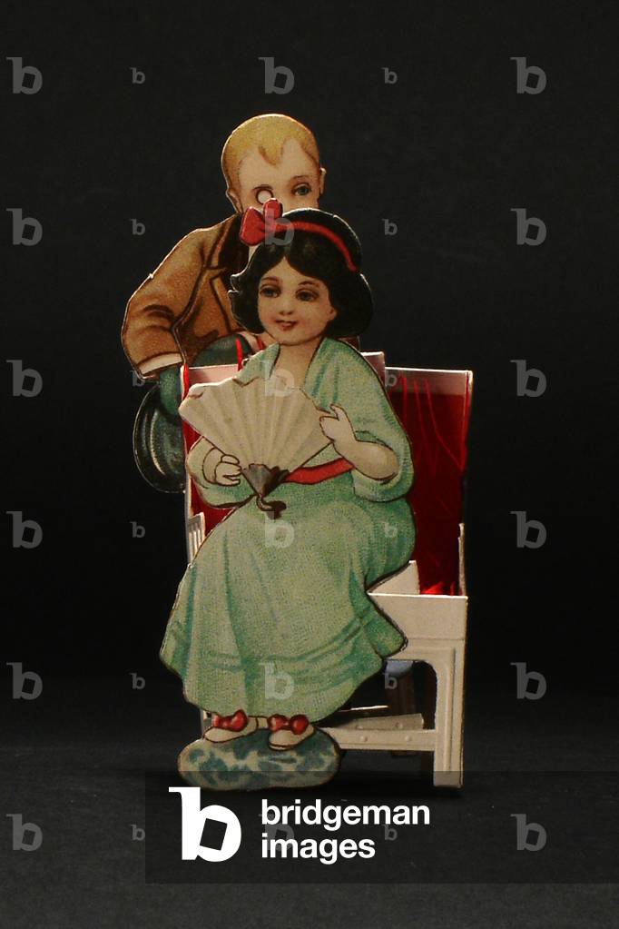 A Victorian die cut honeycomb greeting card of a woman holding a fan and sitting on a chair with a man behind her, c.1880 (colour litho)