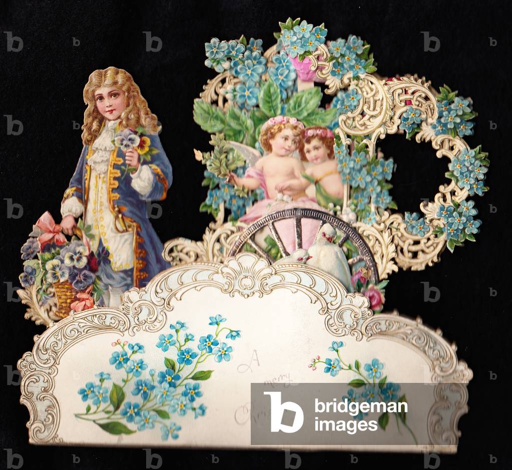A Victorian die cut pop uo Christmas card of a boy in regency costume holding a basket of flowers beside two angels in a cart covered with forget-me-nots, c.1880 (colour litho)