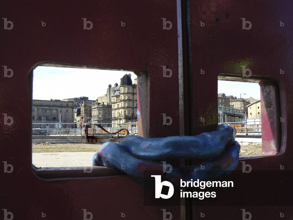 Heavy chained metal doors bar access to site.View of Victorian city opposite.