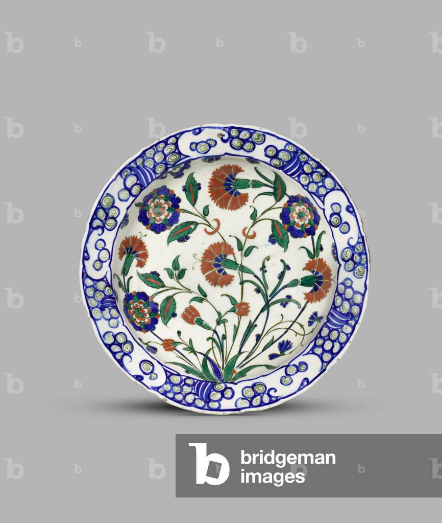 Dish with scalloped rim decorated with carnations, crocus and stylised lotuses within a wave and rock border, c.1575-c.1580 (fritware (cobalt blue, green and bole-red glaze))