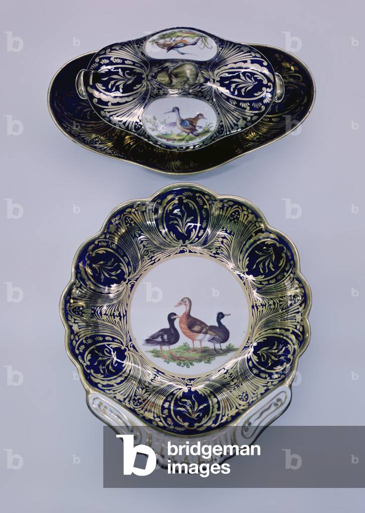 Tureen and stand and a dish from a dessert service, painted panels of birds in colours reserved on blue and gilt ground, c.1810