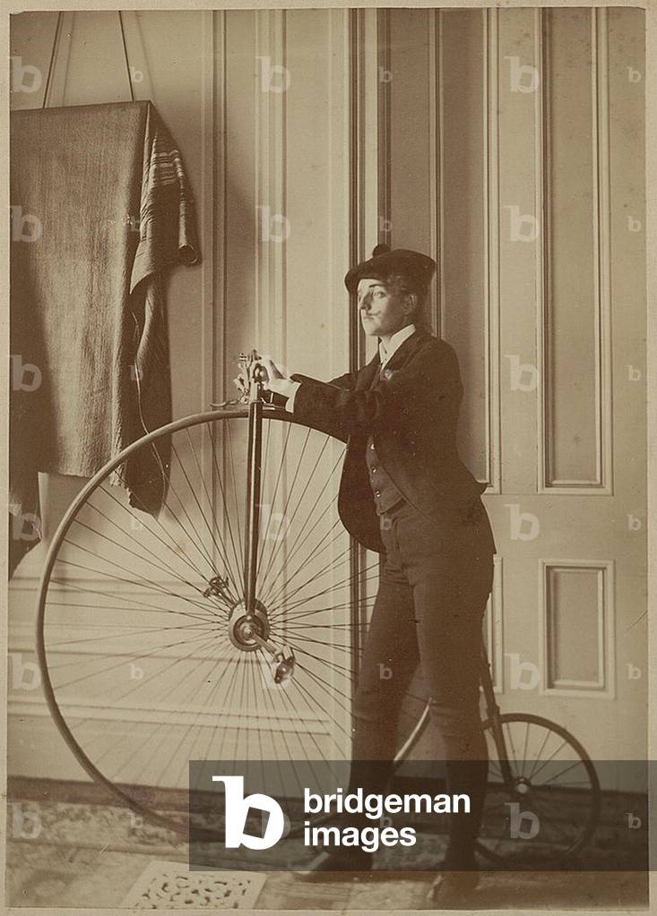 Self portrait of Frances Benjamin Johnston dressed as a man, sporting a fake mustache and holding a bicycle, c.1890 (photo)