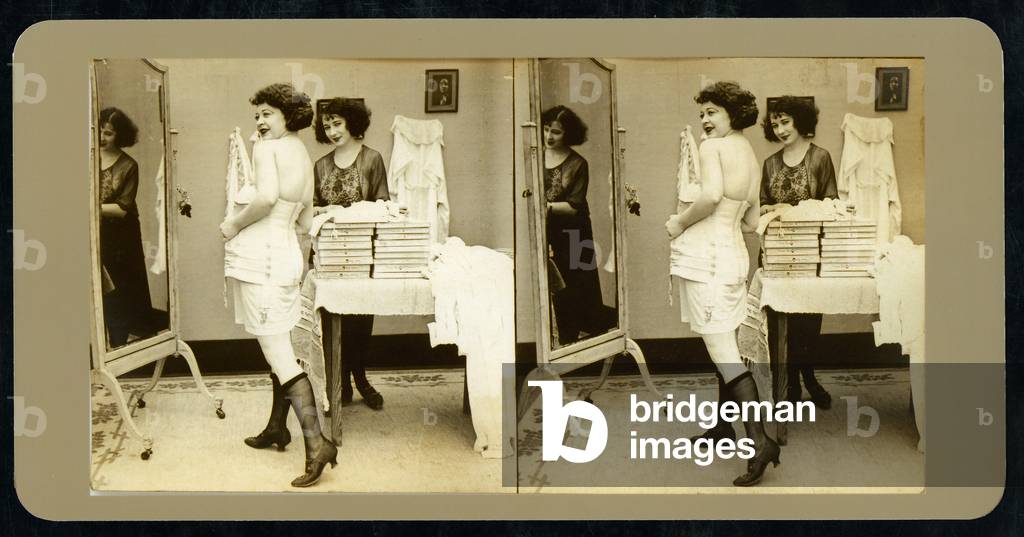 Humorous stereoscopic card depicting a woman trying on corsets in a lingerie shop, c.1900 (sepia photo)