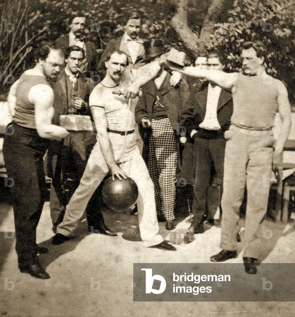 Group Photo of athletes flexing muscles with weights and a medicine ball, c.1910 (sepia photo)