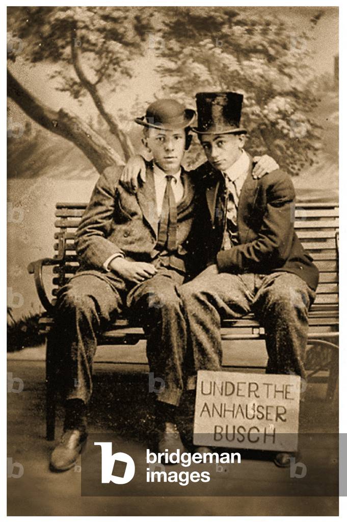 Two men sitting on a bench with sign that reads 