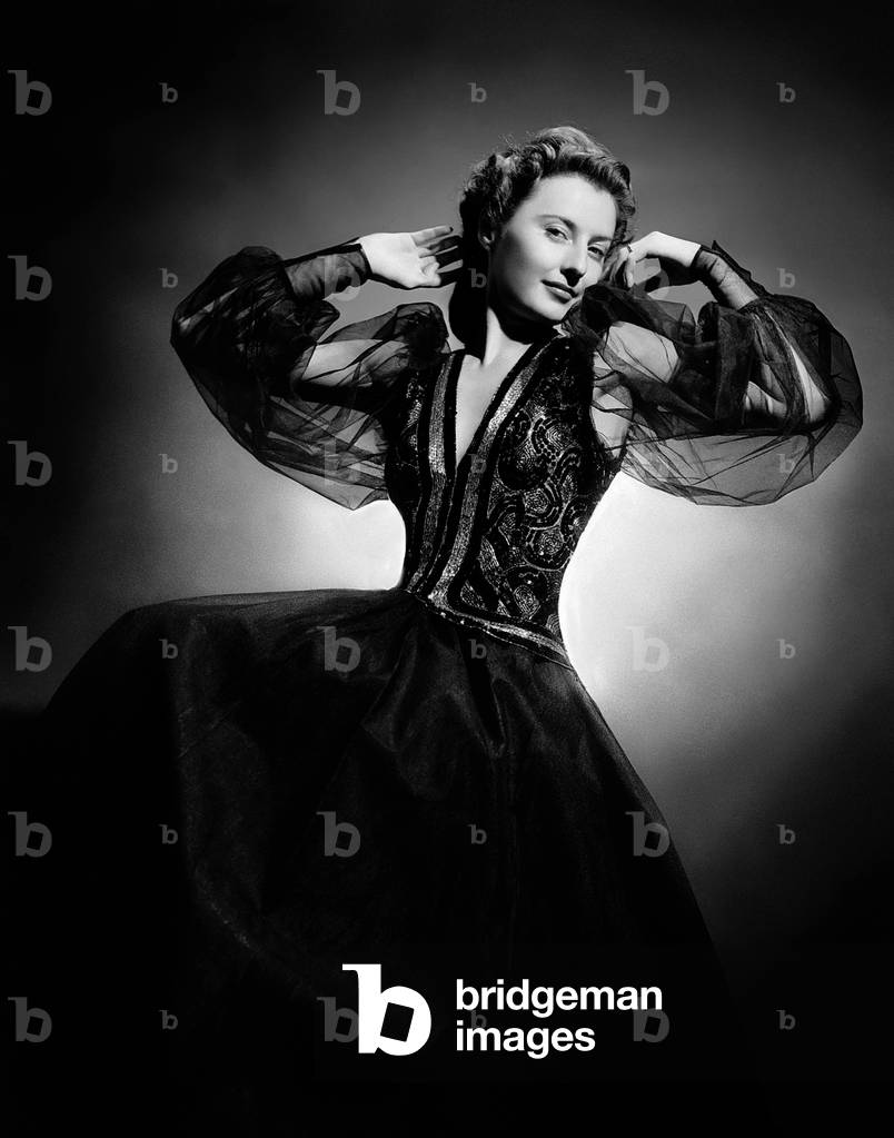1940: American Screen Star Barbara Stanwyck (1907-1990) Wearing A Black Evening Dress With A Sequinned Bustier And Tulle Sleeves.