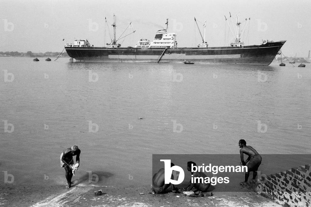 Men washing clothes in the Hoogly River with ship, Kolkata, West Bengal, India, 1977 (b/w photo)