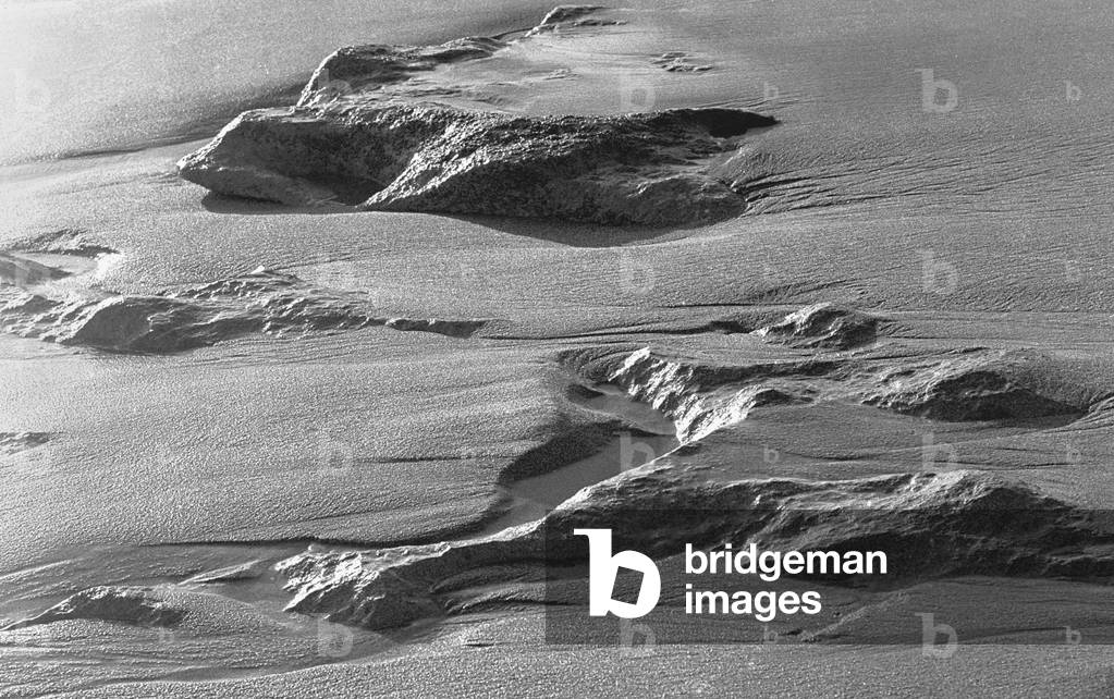 Rock on wet sand (b/w photo)