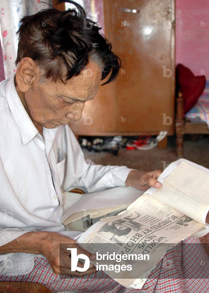 Man reading a newspaper describing the Bhopal disaster, Madhya Pradesh, India, (photo)