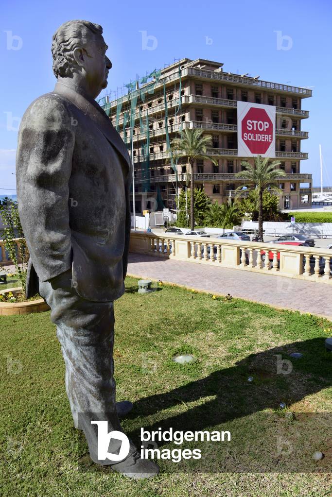 Statue of slain former prime minister Rafiq Hairi (born 1 November 1944-died 14 February 2005) near the Saint-George Hotel, Beirut, the placard adorning its facade continuing to defy ongoing development by real estate company Solidere, founded by Hariri, which could threaten its existence. Beirut, Lebanon (photo)