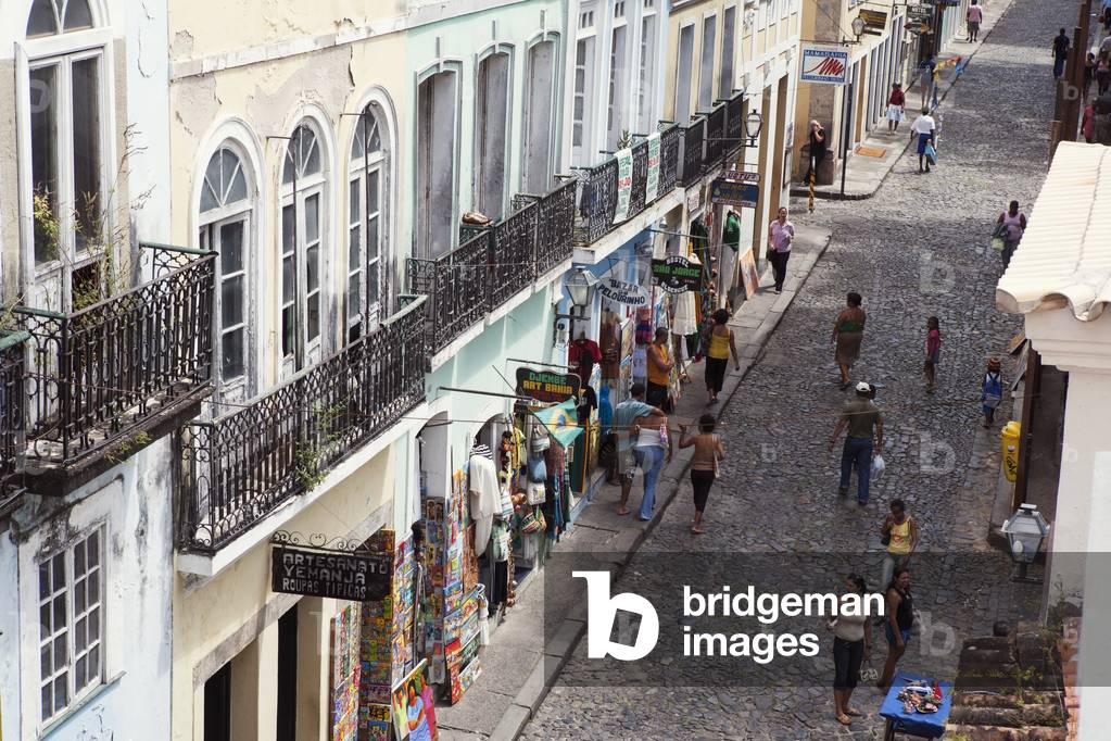Cobbled shopping street in the historical centre of the old colonial city, with paintings and clothes on display and shoppers strolling past, Salvador, Brazil (photo)