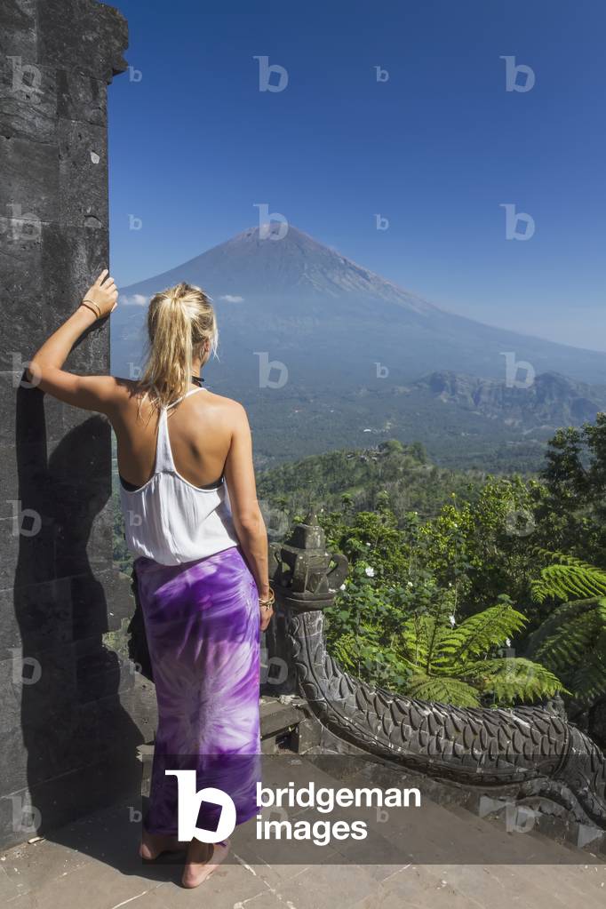 Indonesia, Bali, Young woman looking across to Mount Agung from Lempuyang Temple, Abang (photo)