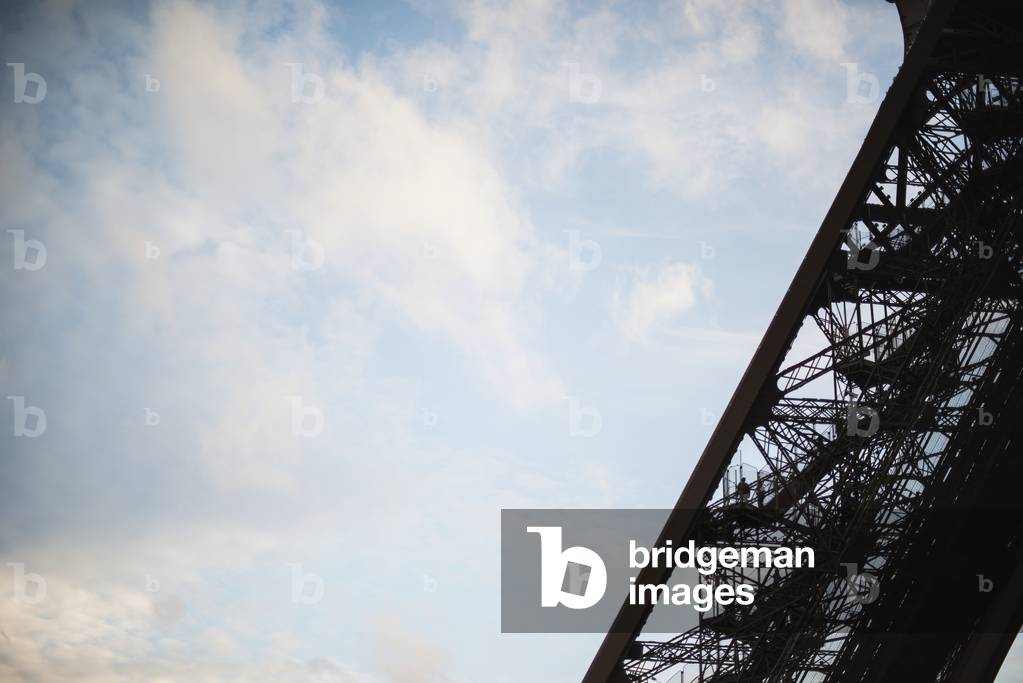 Visitors climb one of the legs of the Eiffel Tower in Paris as the sun sets over the city, Paris, France (photo)