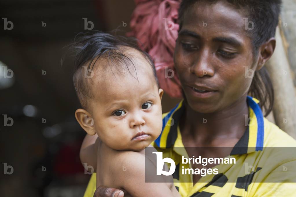 Man holding a baby at the market, Dili, East Timor (photo)