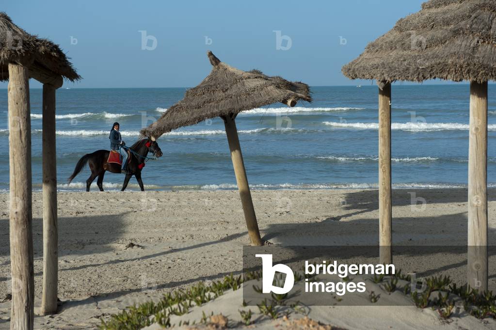 A horse ride operator looking for business from tourists on an almost deserted beach, Djerba, Tunisia (photo)
