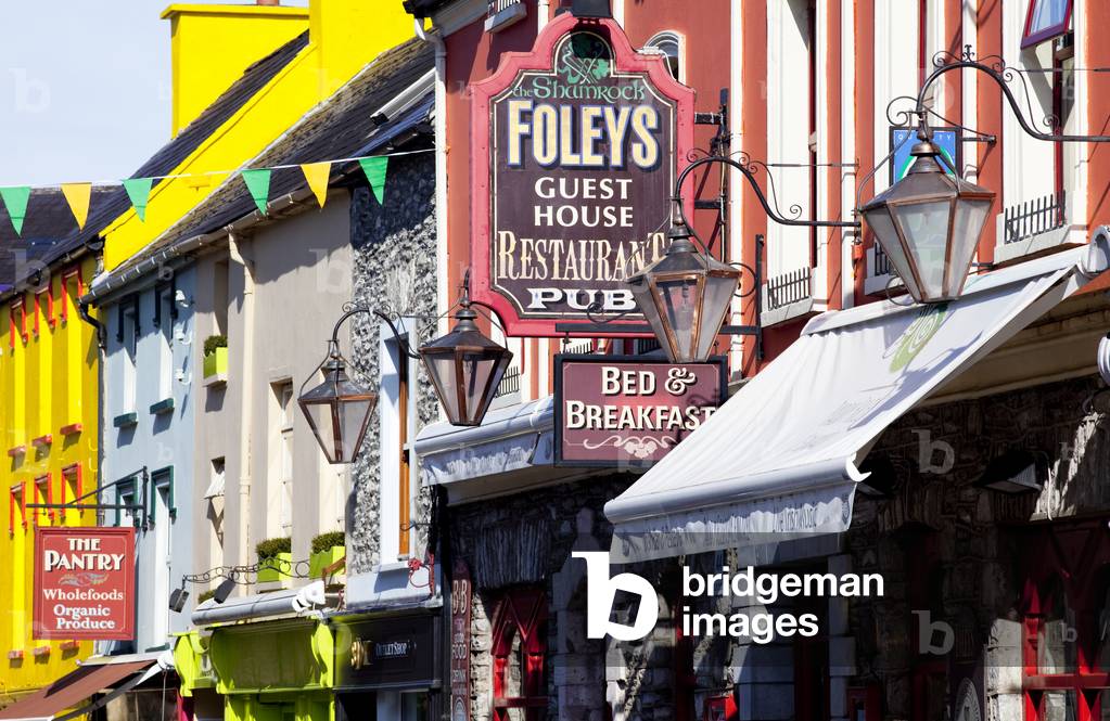 Colourful building facades and signs for restaurants, shops and a bed and breakfast; Kenmare, County Kerry, Ireland (photo)