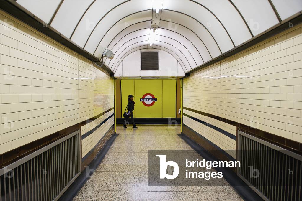 A woman walking at the end of a corridor with arched ceiling in the London Underground, London, England, UK  (photo)
