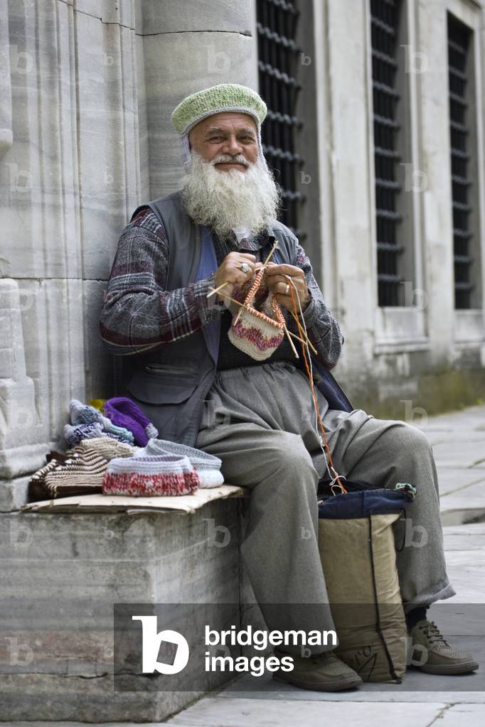 Elderly man knitting traditional wool Fez hats in Sultanahmet district, Istanbul, Turkey 2007 (photo)