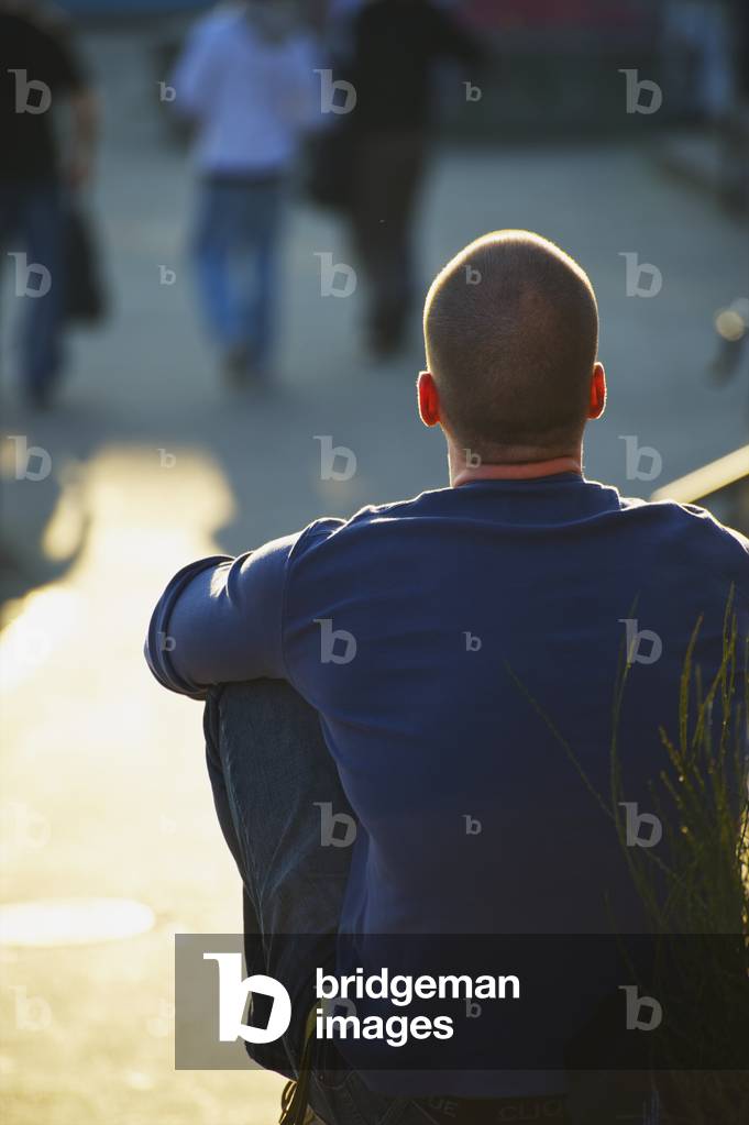 A man sits in the sunshine watching pedestrians, Hamburg, Germany (photo)