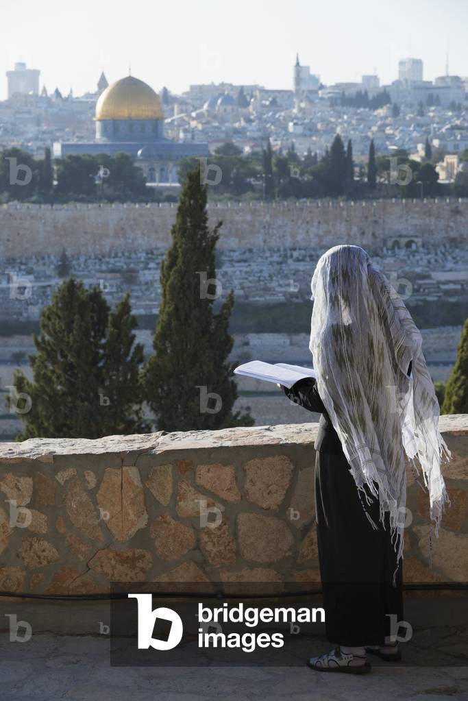 Israel, Pilgrim praying on Mount of Olives facing Old City, Jerusalem (photo)