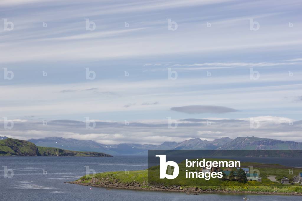 Houses on a small peninsula with mountains and ocean in the background, Sand Point, Southwestern Alaska, USA, Summer (photo)
