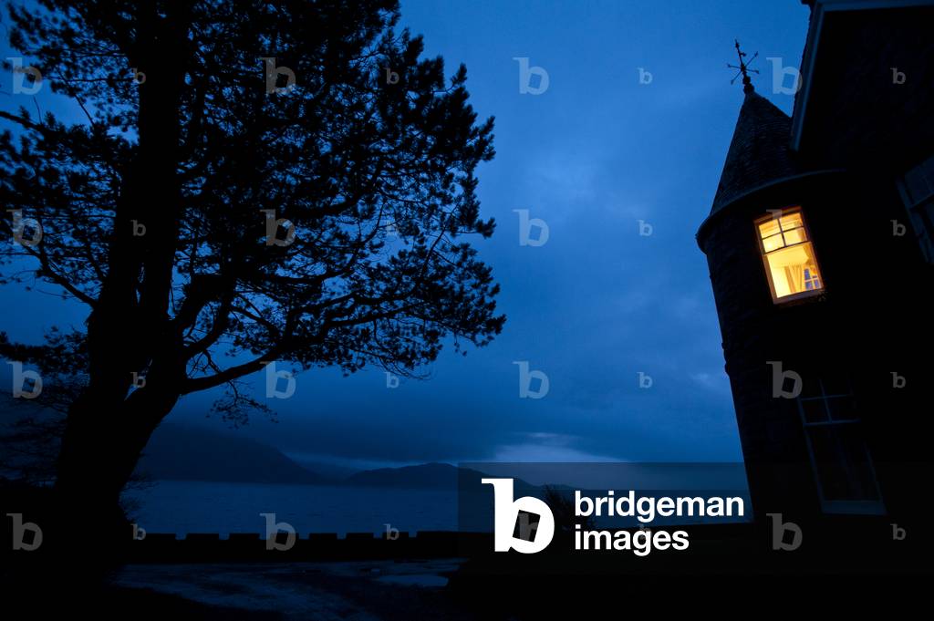 Light in turret of house at dusk, Onich, Highlands, Scotland (photo)