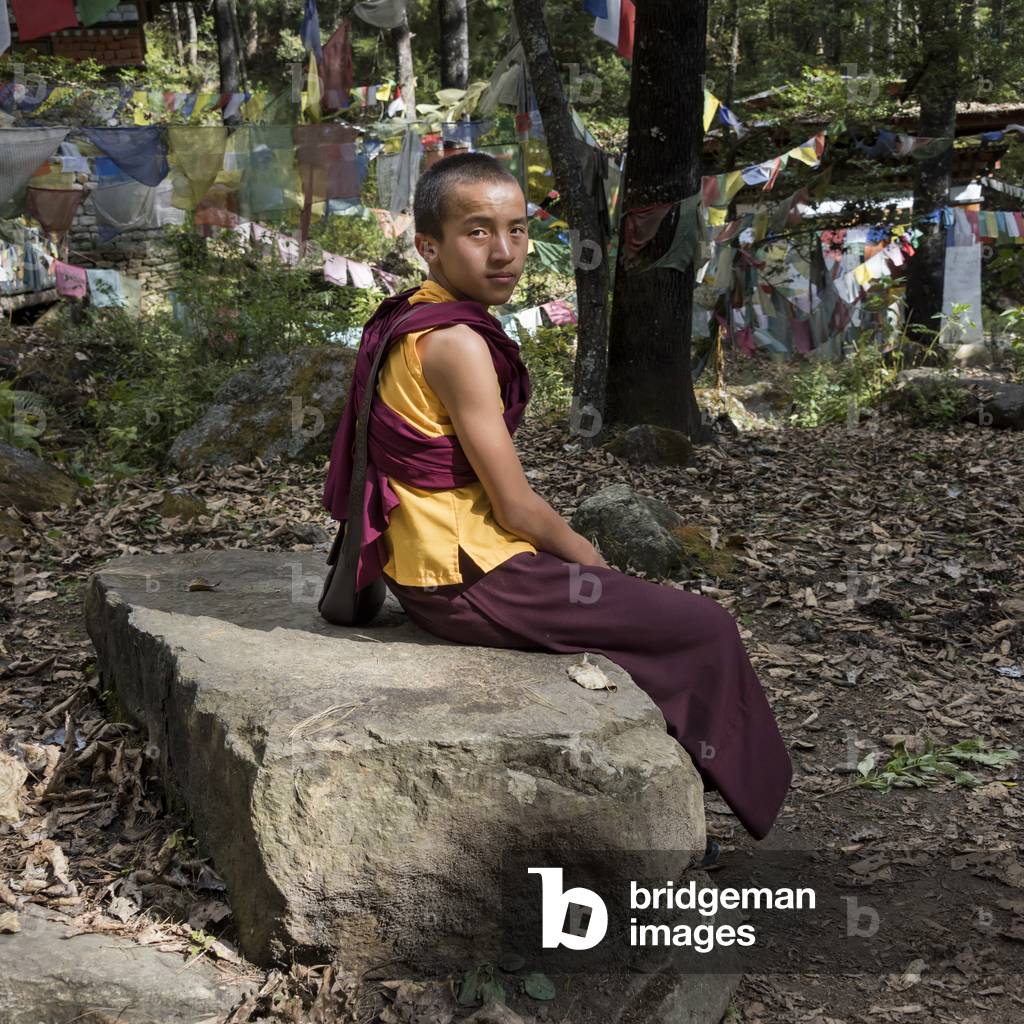 A young monk sitting on a rock, Paro, Bhutan (photo)