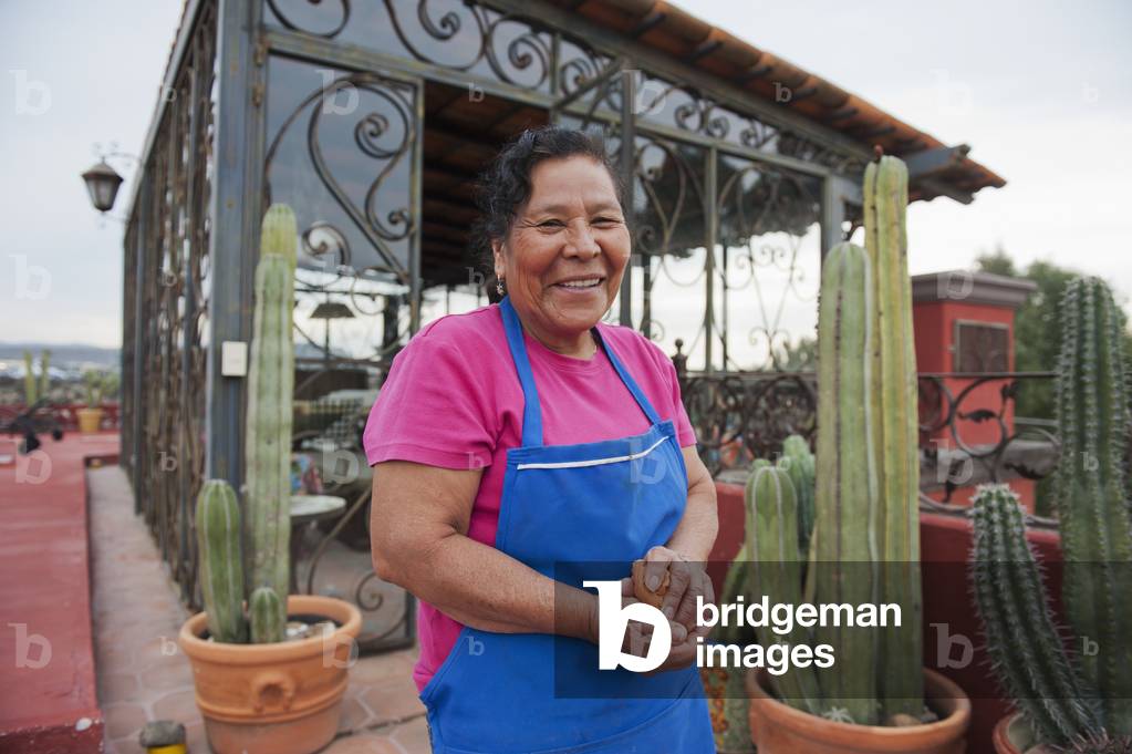 Maid standing on rooftop terrace wearing apron, San Miguel de Allende, Guanajuato, Mexico (photo)
