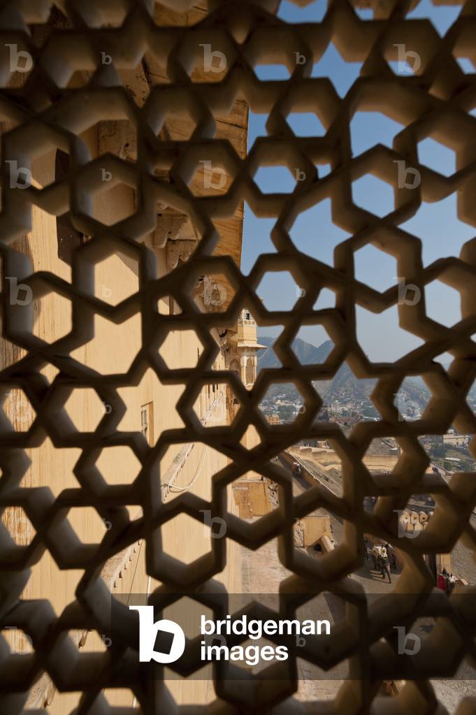 Looking through stone lattice window to the walls of Amber Fort, Amer, Jaipur, India (photo)