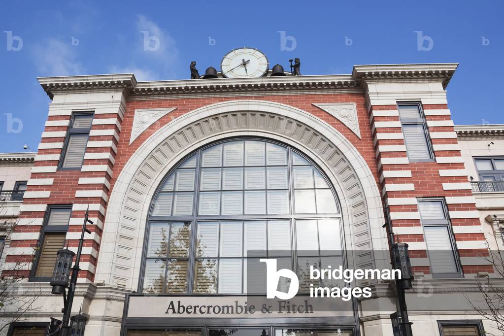 A clock and brick facade of a retail building with an arched window, California, USA (photo)