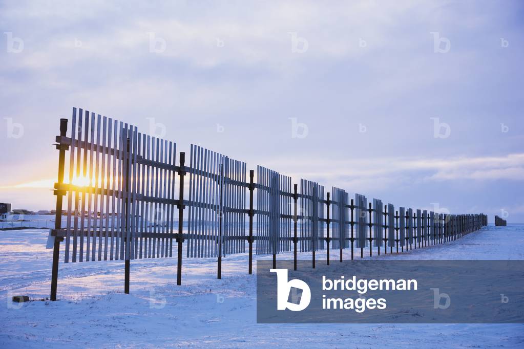 Sun setting behind a snow fence, Barrow, Winter, Arctic Alaska, USA (photo)