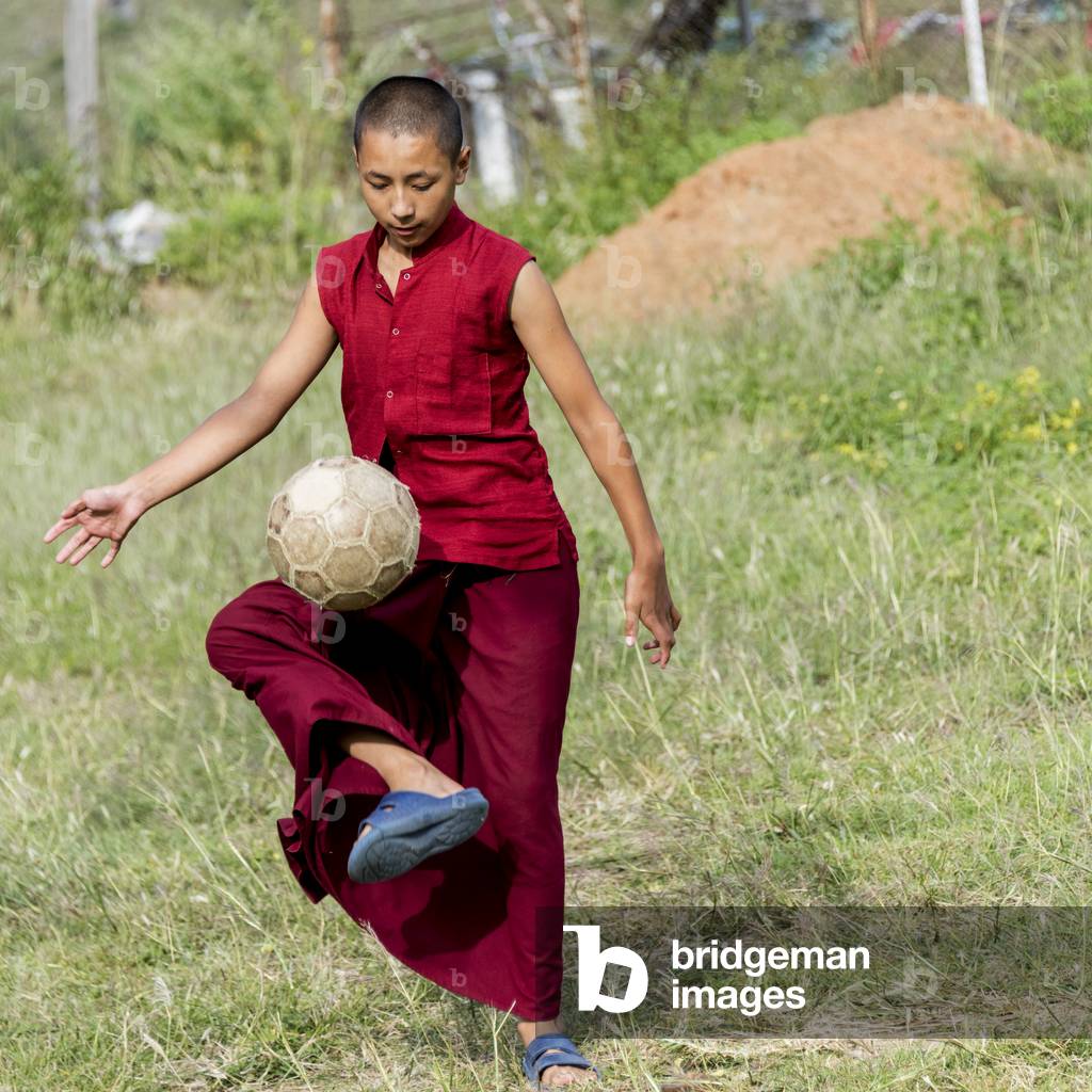 A young monk plays with a soccer ball, Punakha, Bhutan (photo)