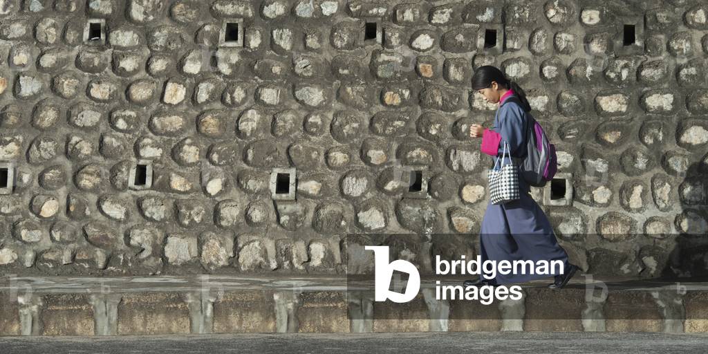 Woman walking by Stone Building, Thimphu Bhutan (photo)
