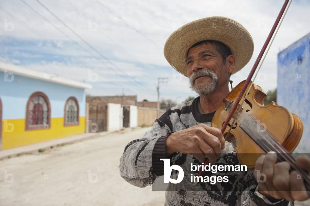 Man playing violin on small town dirt road, Guanajuato, Mexico (photo)