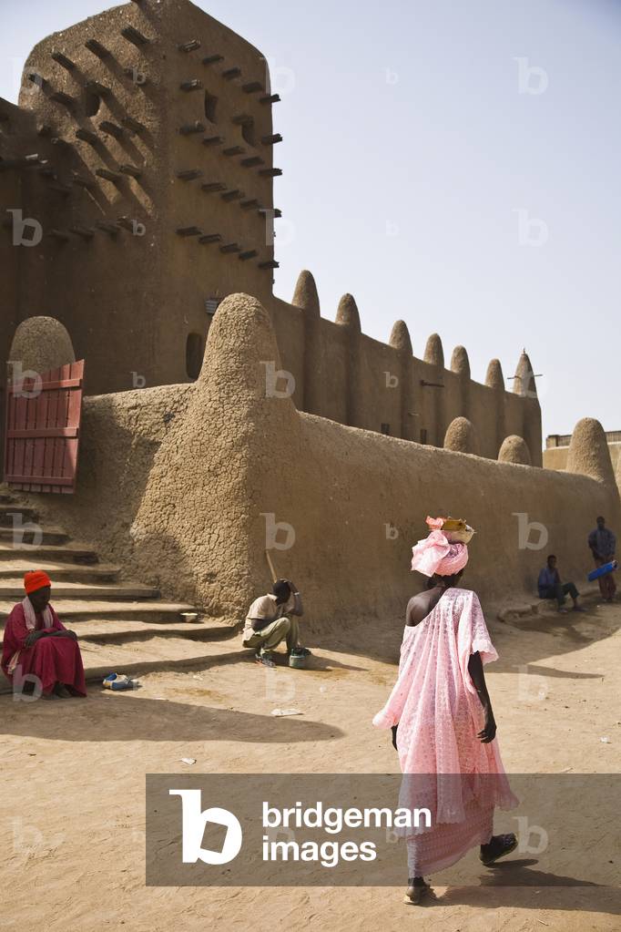 Woman in Pink Gown Walking in Front of Djenne Mosque (photo)