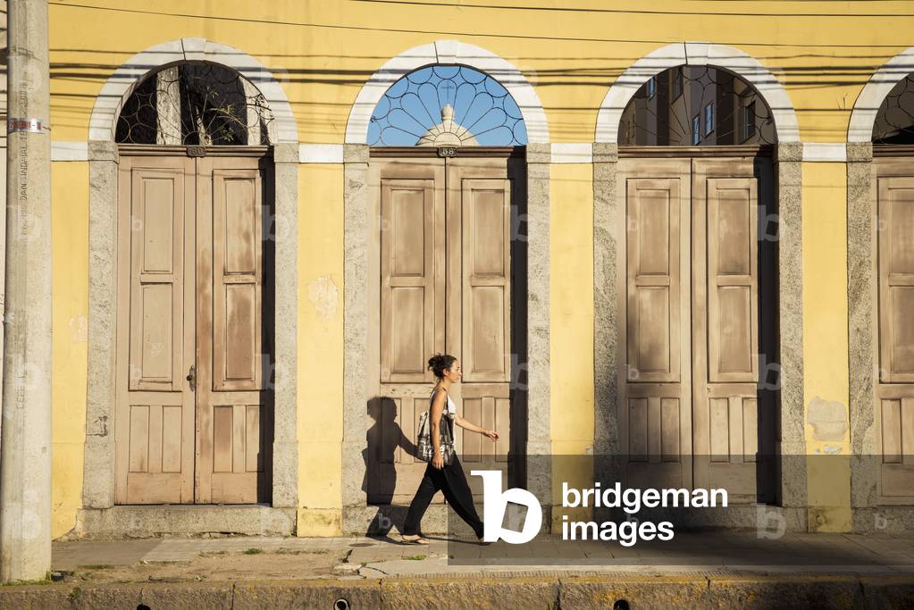 Brazil, Rio Grande do Sul, Praca General Osorio, Pelotas, Young woman walking on street (photo)