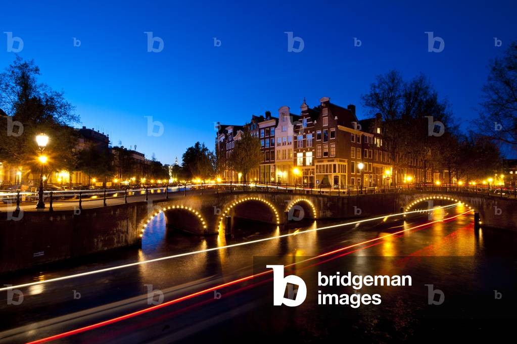 Bridges over canals at dusk with streak of lights from boat, Amsterdam, Holland (photo)