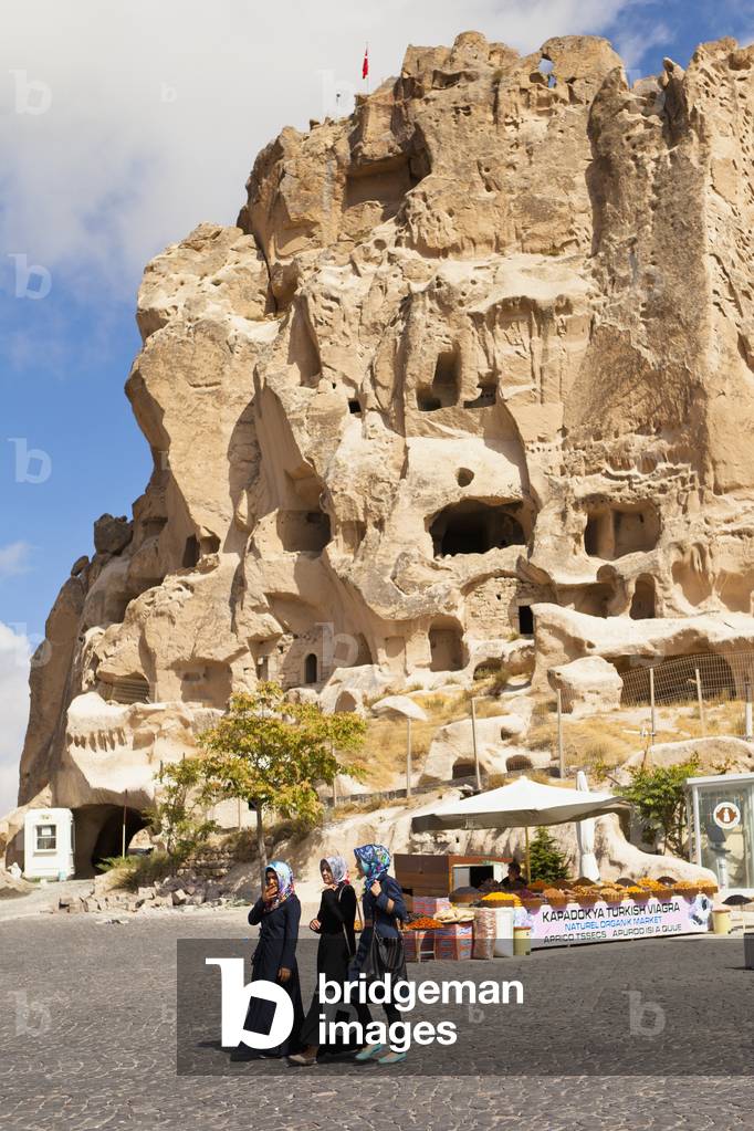 Three young women walk on the road with Uchisar Castle in the background, Uchisar, Cappadocia, Turkey (photo)