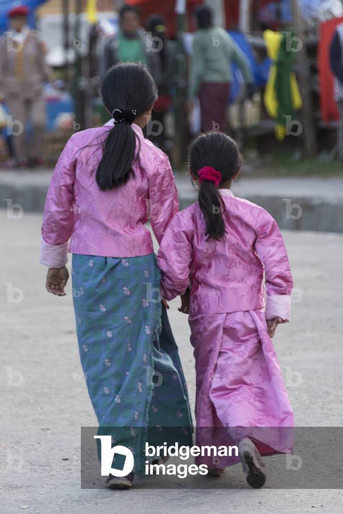 Two young girls walking down a street together in traditional clothing, Paro, Bhutan (photo)