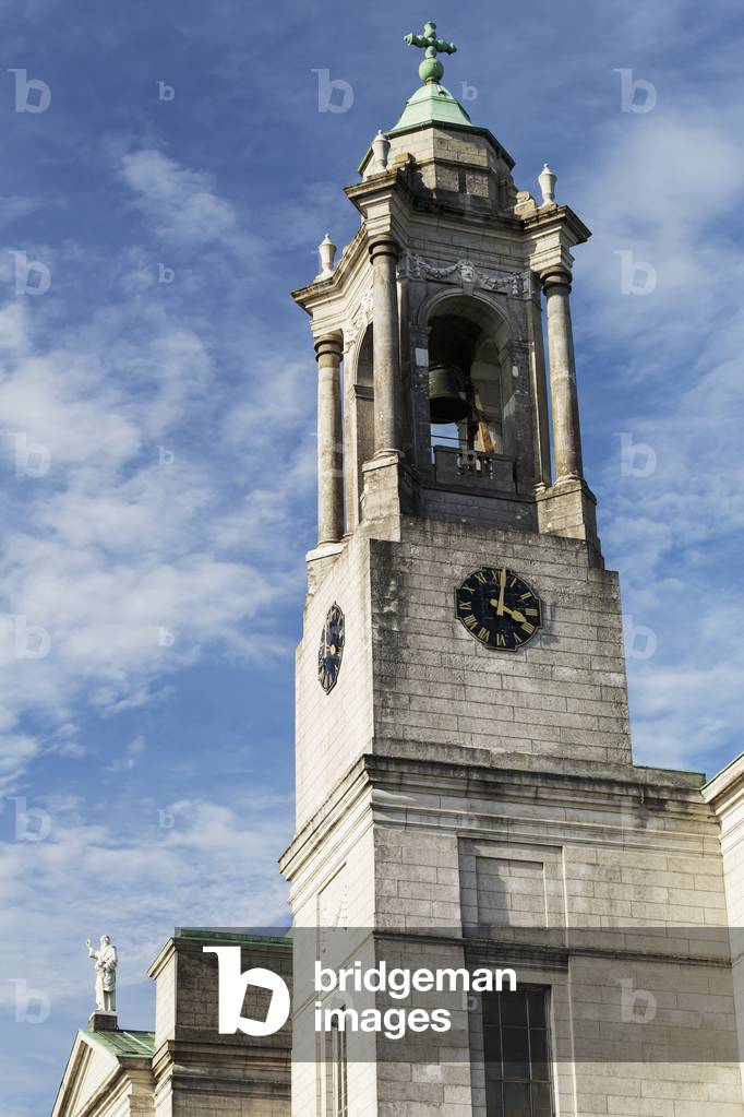 Stone church steeple and bell tower with clouds and blue sky; Athlone, County Westmeath, Ireland (photo)