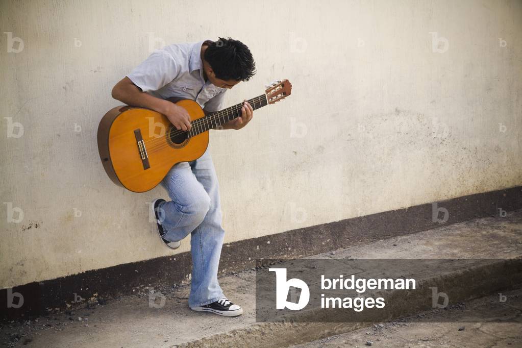 Man leaning against a Wall Playing Guitar, Patzicia, Guatemala (photo)