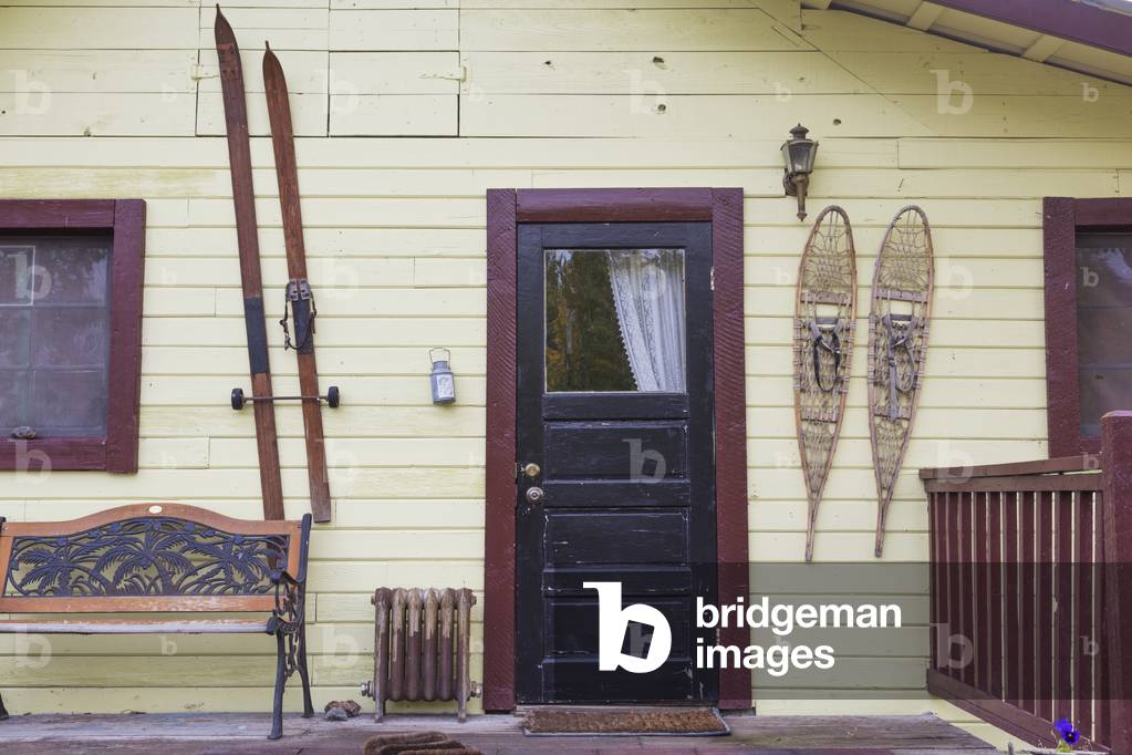 Old house with skis and snowshoes hanging by the front door; McCarthy, Alaska, United States of America (photo)
