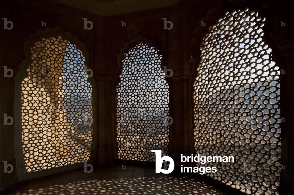 Looking through stone lattice window to the walls of Amber Fort, Amer, Jaipur, India (photo)