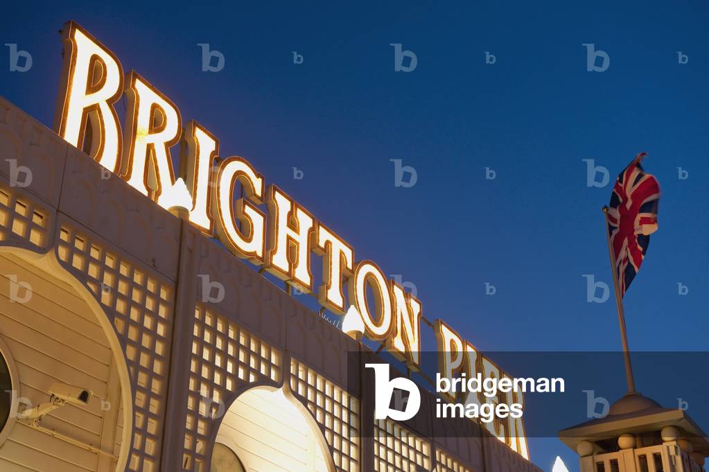 Low angle view of a Brighton pier sign lit up at dusk, East Sussex, UK., East Sussex, UK. (photo)