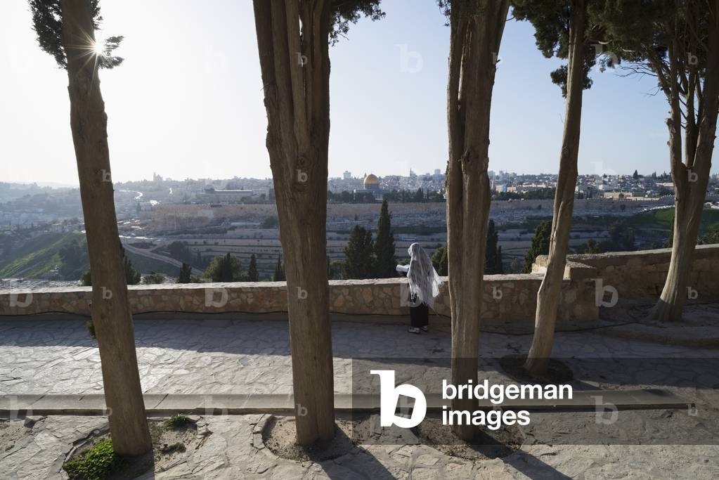 Israel, Pilgrim praying on Mount of Olives facing Old City, Jerusalem (photo)