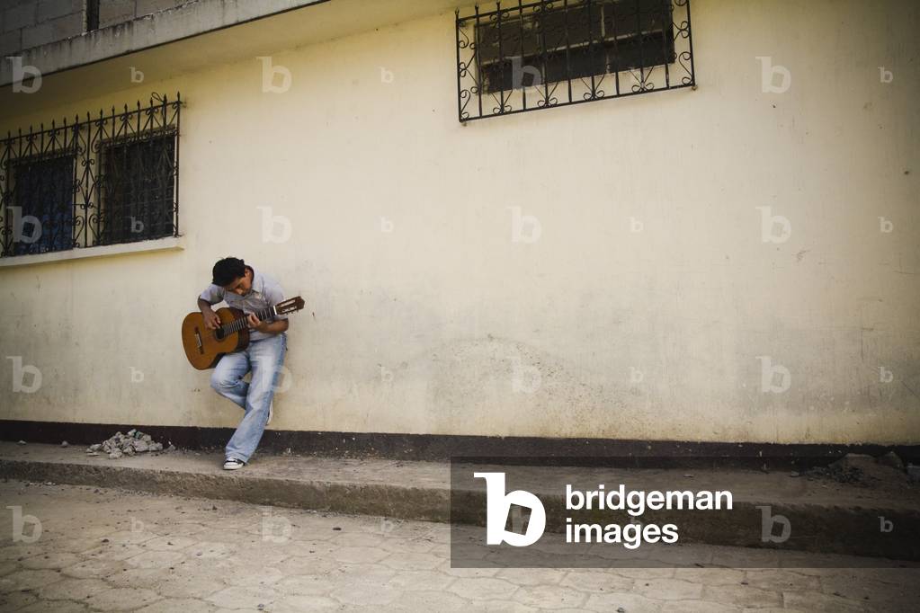 Man leaning against a Wall Playing Guitar, Patzicia, Guatemala (photo)
