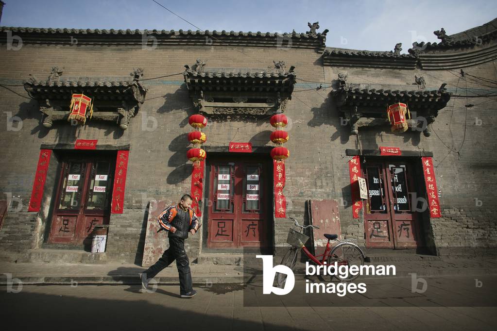 A Local Boy Running Beside A Bicycle  and Traditional Chinese House in Pingyao, A Unesco World Heritage Site, Shanxi Province, China (photo)