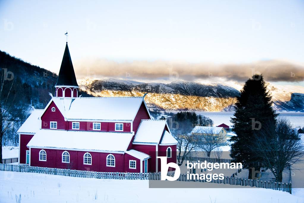 Traditional red Norwegian church, in the village in winter with snow, Ortnevik, Sognefjord, Norway (photo)