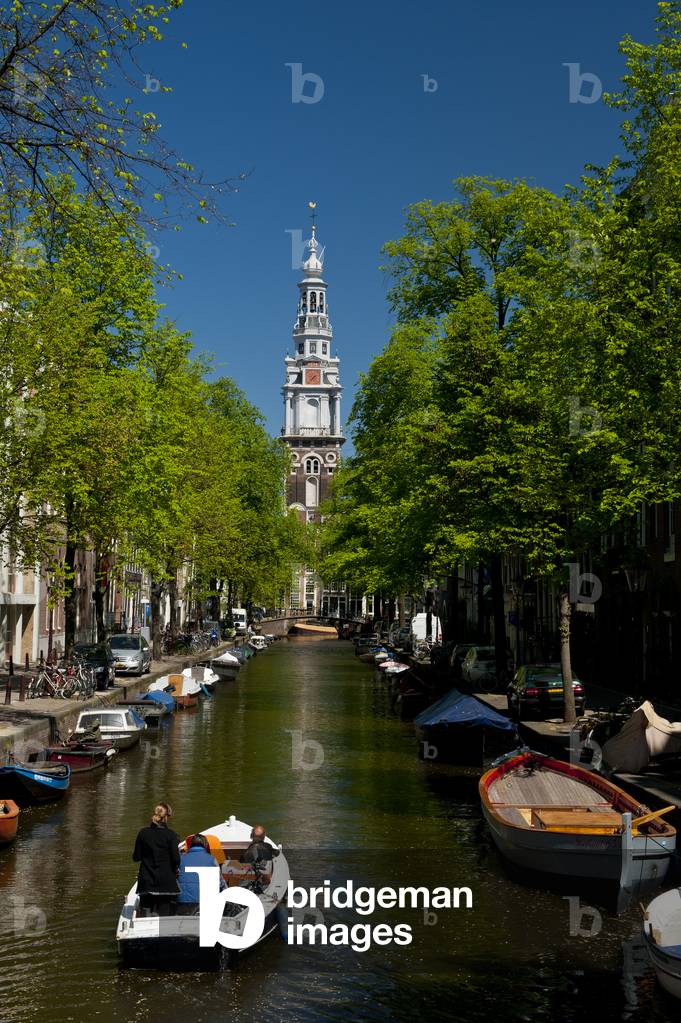 People in small boat going along small canal with spire of the Zuiderkerk church behind, Amsterdam, Holland (photo)